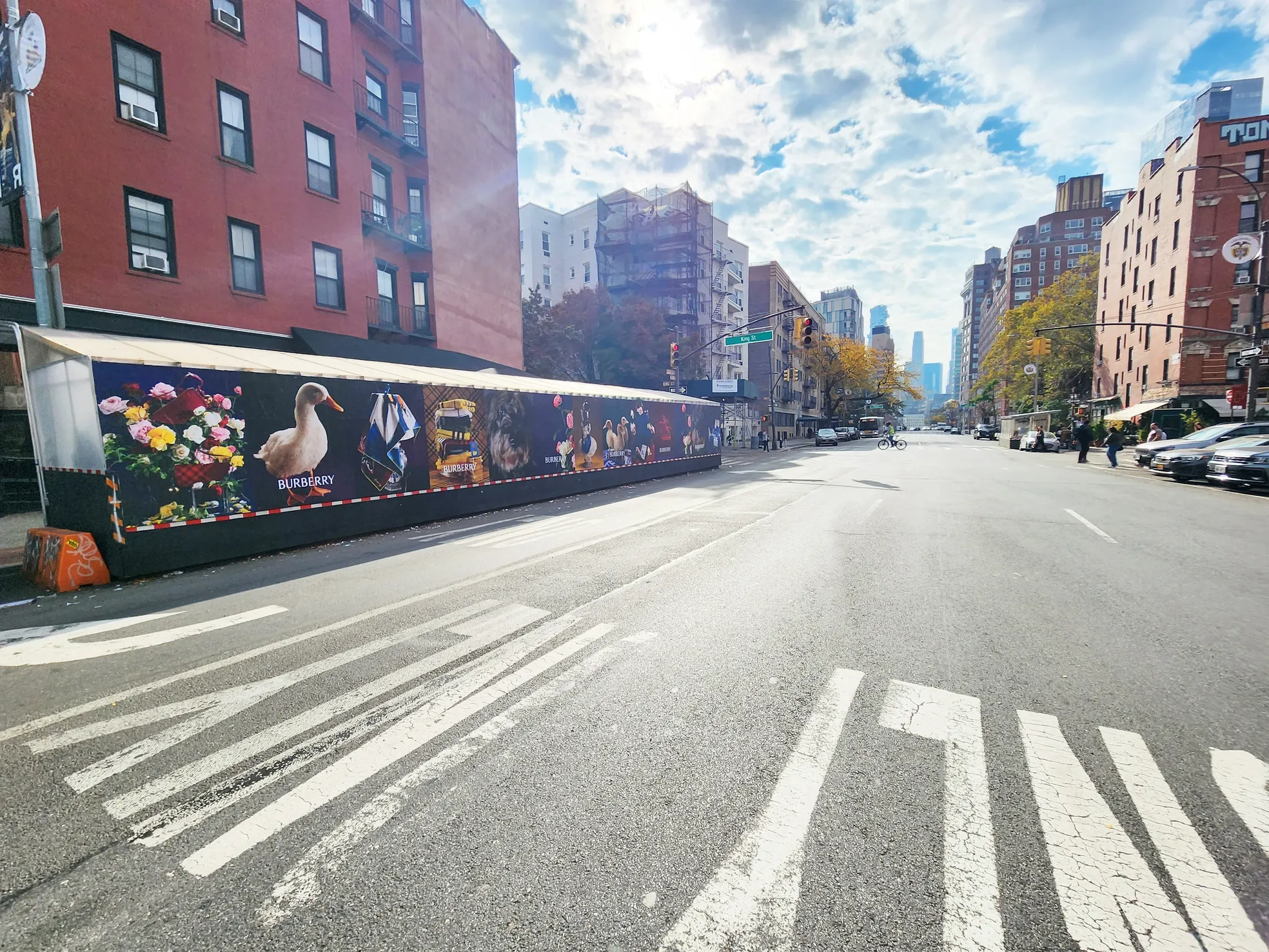 Sidewalk dining structure wrapped in large-format advertising on a New York City street