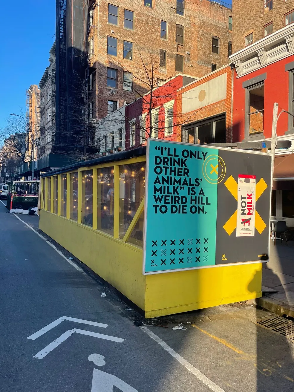 Yellow outdoor dining shed wrapped in a beverage brand advertising campaign